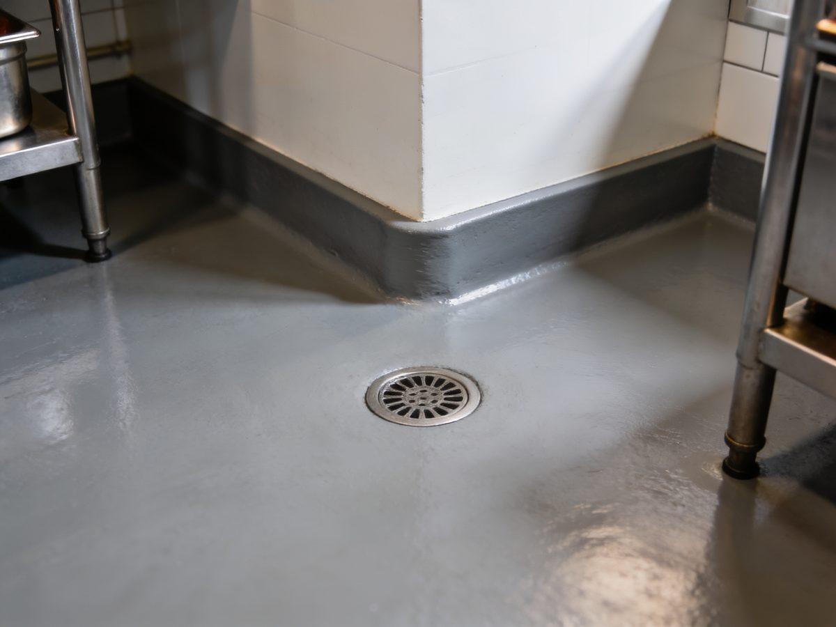 A commercial kitchen floor in seamless urethane cement with a coved base and a floor drain